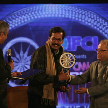 J Gopikrishnan receiving CNN-IBN's Indian of the Year (Special Category) from Finance Minister Pranab Mukherjee in December 2010. CNN-IBN Editor Rajdeep Sardesai is also seen